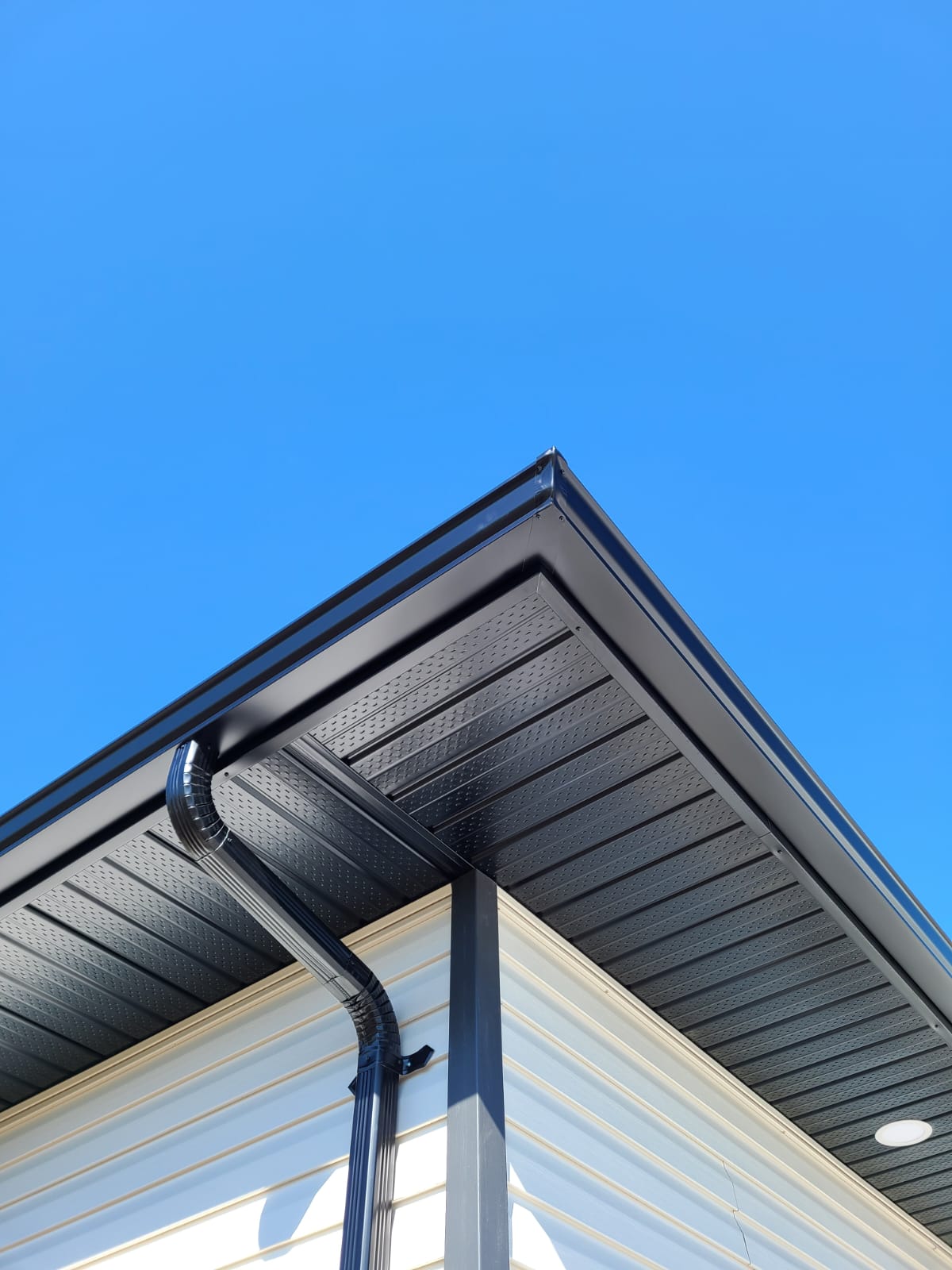 Fresh black eavestroughs against a blue sky